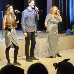Muzikinis festivalis-konkursas "Muzikoje - mes šeima" dvi moterys ir vienas vaikinas dainuoja