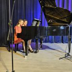 Muzikinis festivalis-konkursas "Muzikoje - mes šeima" raudonai apsirengusios mergaitės groja pianinu